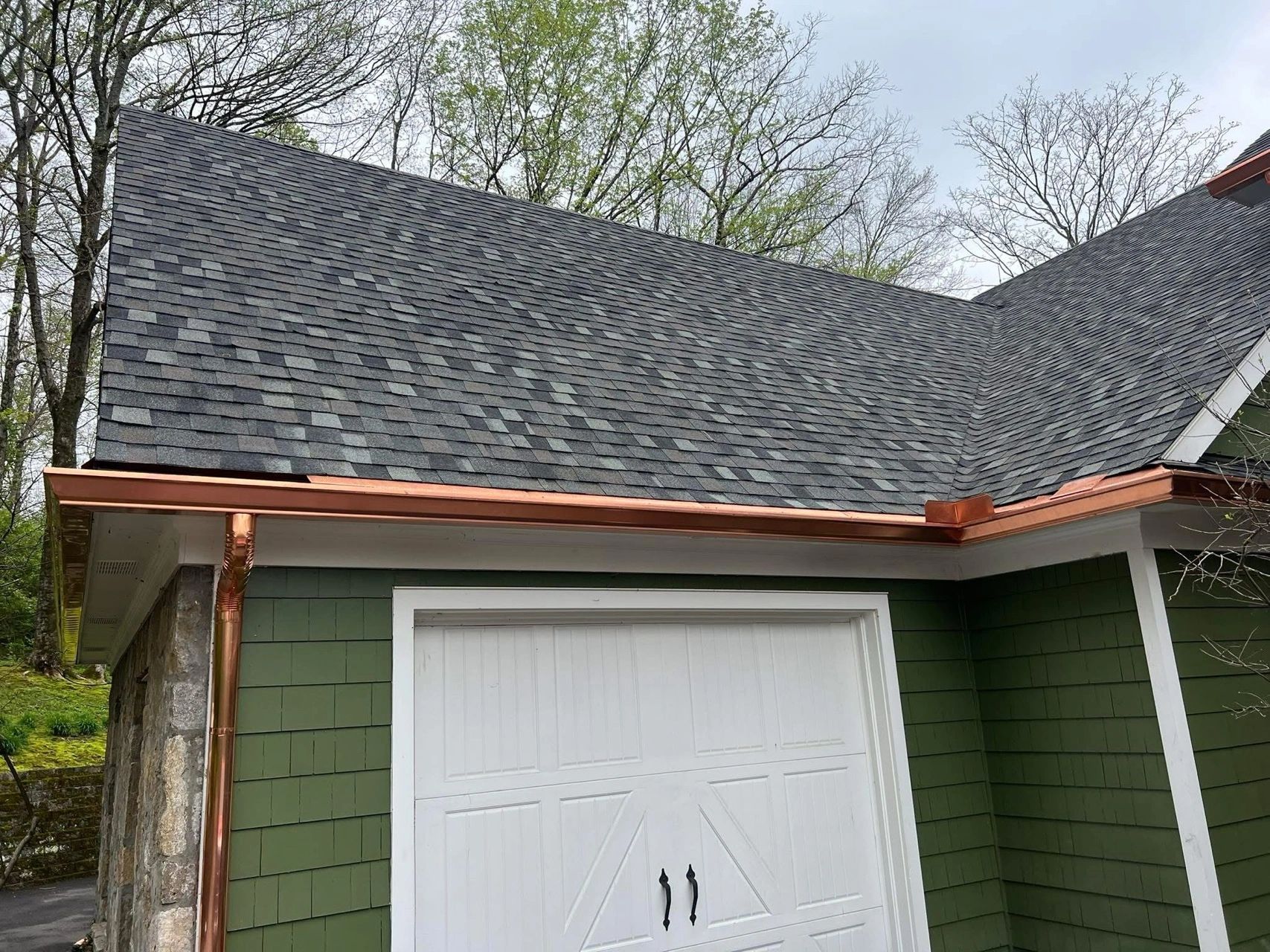 Residential garage with new dark gray asphalt shingle roof and copper gutters
