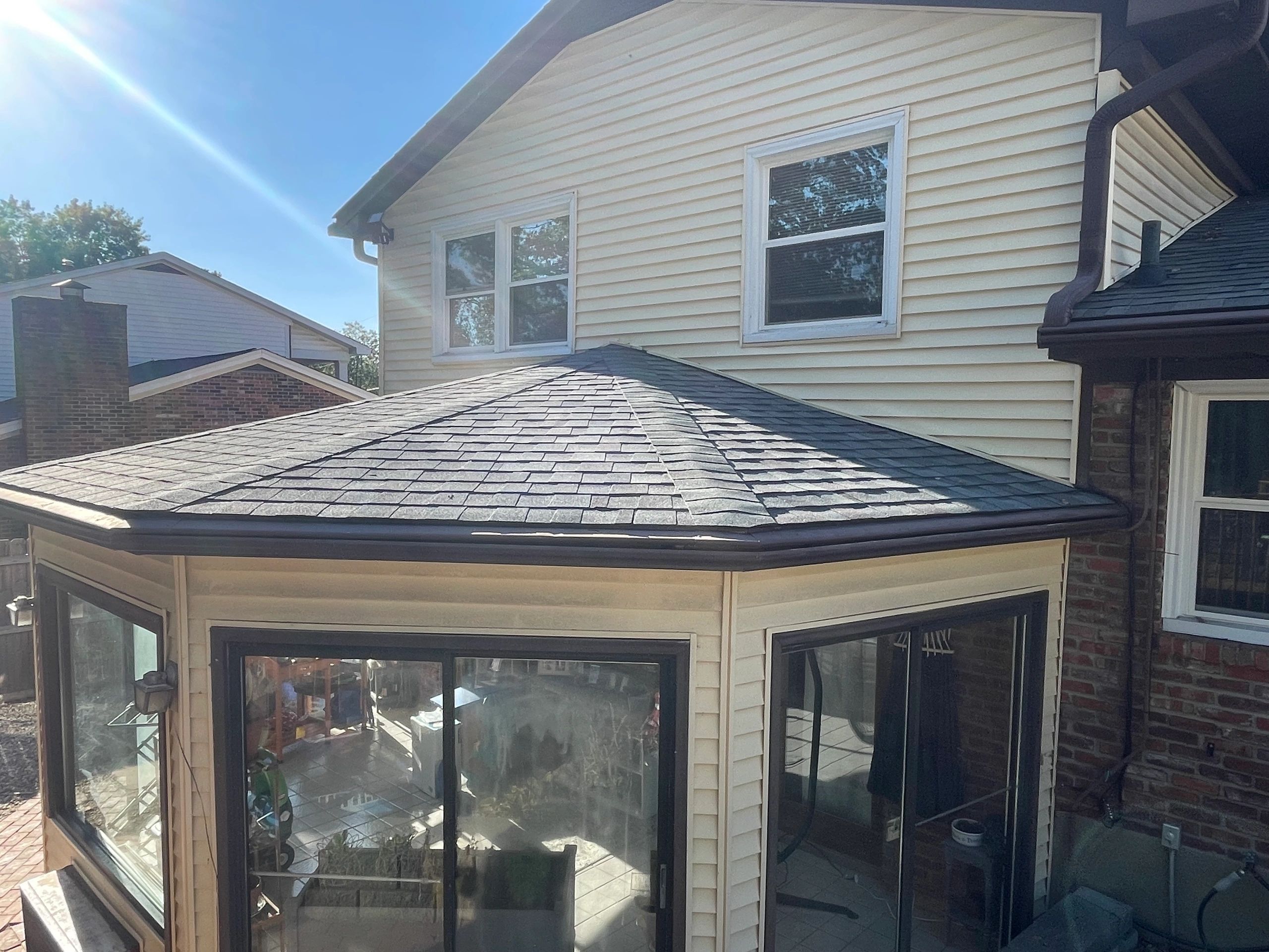 Residential home with newly installed sunroom and dark shingled roof